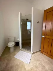 Bathroom with walk-in shower, toilet and white bath mat in Casita 5