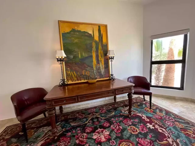 Sitting area with wooden table, two chairs, artwork and patterned rug in Casita 5