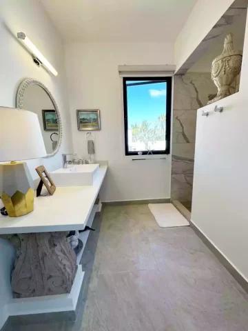 Casita 6 bathroom with white vanity, round mirror and walk-in shower