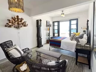 Casita 7 living room with wicker seating, colorful decor, and ocean view at Lejos de Todo
